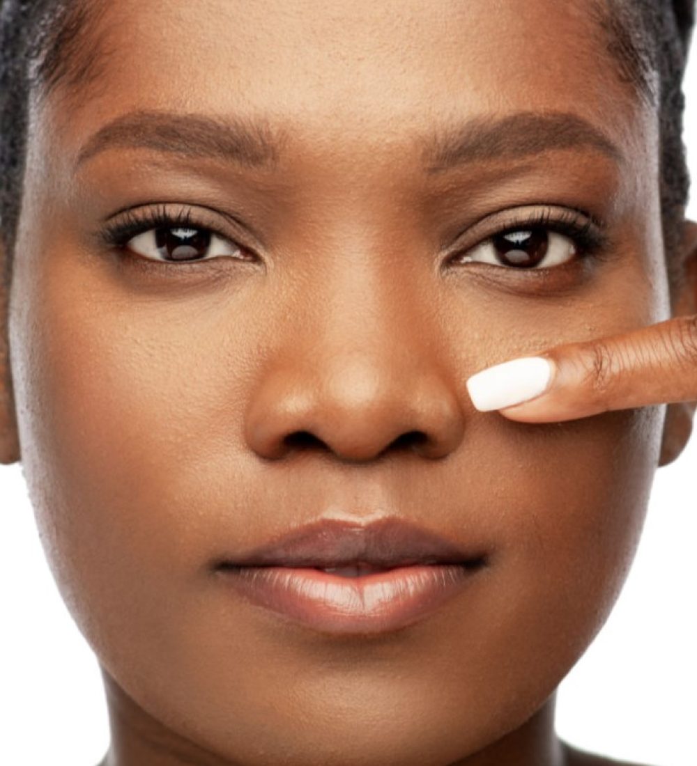 beauty and people concept - portrait of young african american woman with bare shoulders pointing to her nose over white background