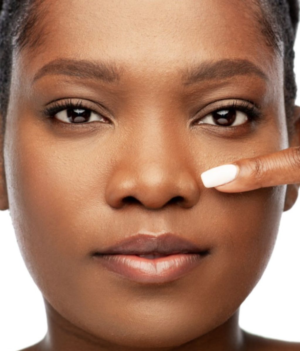 beauty and people concept - portrait of young african american woman with bare shoulders pointing to her nose over white background